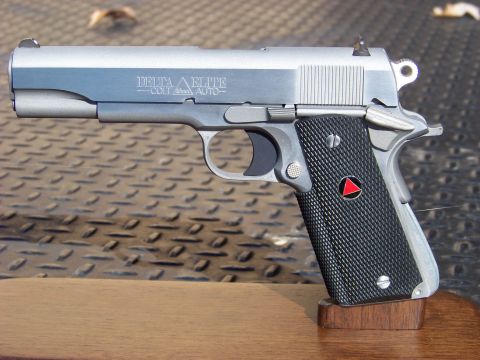 1995 Mercury Grand Marquis - A close-up, side profile view of a Colt Delta Elite 10mm Auto pistol resting on a wooden stand. The pistol has a silver finish and black ch…