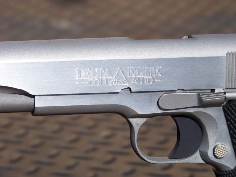 1995 Mercury Grand Marquis - A close-up, side view of a silver-colored handgun with "DELTA ELITE" and "COLT AUTO" engraved on the slide.