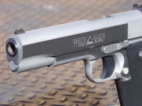 1995 Mercury Grand Marquis - A close-up, angled shot of the slide and barrel of a Colt Delta Elite 10mm Auto pistol. The pistol has a two-tone finish with a matte silve…