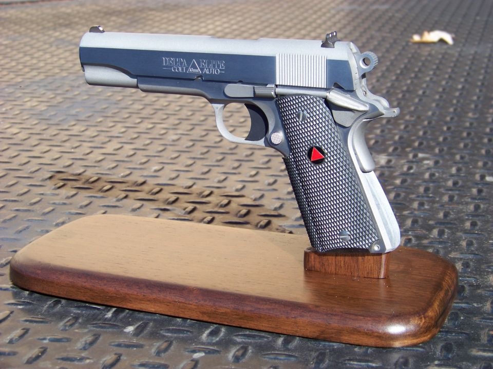 Colt Delta Elite 10mm Auto pistol on a wooden display stand.
