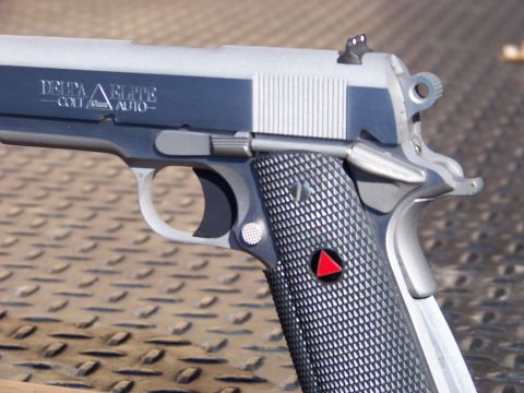 1995 Mercury Grand Marquis - A close-up of a silver and dark blue semi-automatic pistol with "DELTA ELITE COLT AUTO" text visible on the slide. The pistol has textured…