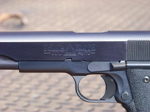 1995 Mercury Grand Marquis - A close-up, side profile of a handgun with "DELTA" and "COLT 10mm AUTO" engraved on the slide.