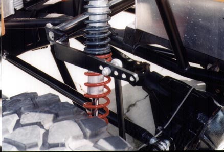 1990 Ford Bronco - Close-up of a vehicle's suspension system, showing a red coilover shock and part of a large off-road tire.