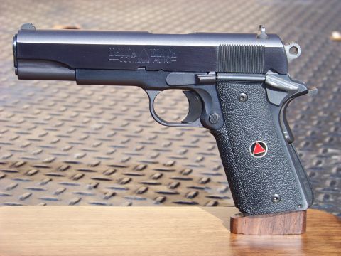1995 Mercury Grand Marquis - A close-up, side view of a black semi-automatic pistol with "DELTA ELITE" and "COLT 10mm AUTO" text visible on the slide. The pistol has te…