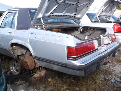 1999 Mercury Grand Marquis - The rear quarter panel and trunk of a silver sedan are visible, with the trunk open. White text that reads "50-892" is written on the quart…
