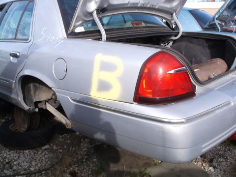 1999 Mercury Grand Marquis - The rear quarter panel of a silver sedan shows a yellow spray-painted letter 'B' and white handwritten text '5-1039'. The trunk is open, re…
