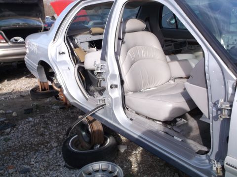 1999 Mercury Grand Marquis - The interior of a silver sedan is shown with the driver's side door open. The car is missing its front wheels and is propped up on wooden b…