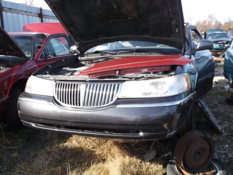 1999 Mercury Grand Marquis - The front end of a dark gray sedan with its hood open is shown, revealing the engine bay and a red engine cover. A red sedan with its hood…