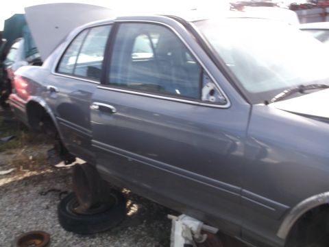 1999 Mercury Grand Marquis - The side view of a gray sedan with the hood open shows the car is missing its side mirror and has had its wheels removed. The vehicle appea…