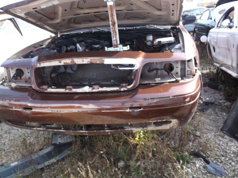 1999 Mercury Grand Marquis - The front end of a brown 1999 Mercury Grand Marquis is shown with the hood open, revealing the engine bay. The headlights and grille are mi…