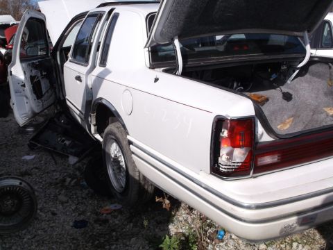 1999 Mercury Grand Marquis - The rear passenger side of a white sedan is shown with the trunk and driver's side door open. The taillight is broken and the interior of t…