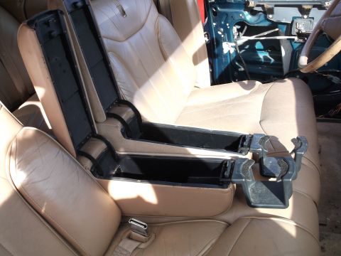 1999 Mercury Grand Marquis - The interior of a car shows tan leather seats with an open center console. The console has two storage compartments and a cup holder assemb…