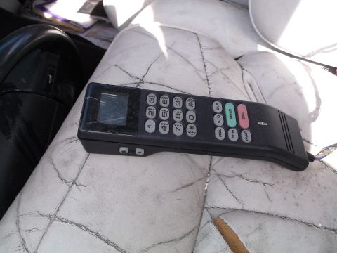 1999 Mercury Grand Marquis - A vintage car phone is resting on a cracked white leather seat, next to a black steering wheel.