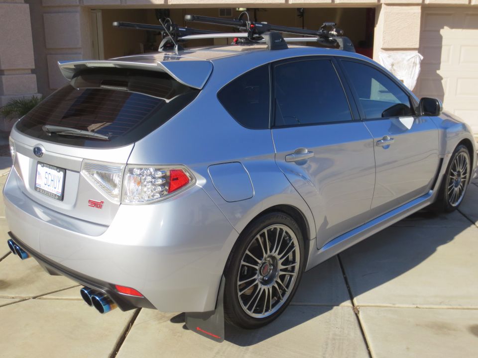 Silver Subaru Impreza WRX STI hatchback with roof rack and aftermarket exhaust.