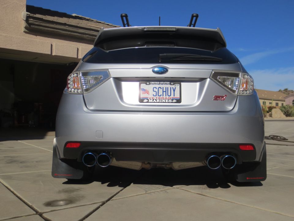 Silver Subaru Impreza WRX STI hatchback rear view with custom license plate and dual exhaust.