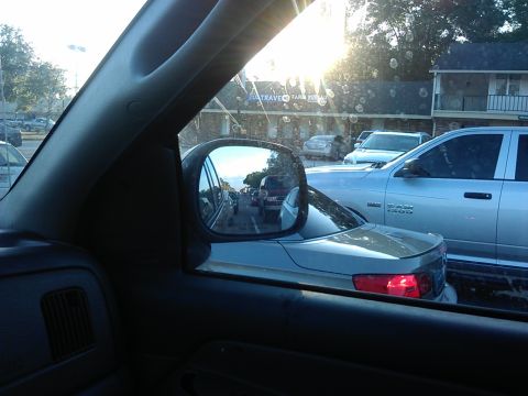 1994 Ford Bronco - View through the driver's side window of a silver pickup truck, possibly a Dodge Ram, in traffic. The side mirror reflects other vehicles a…