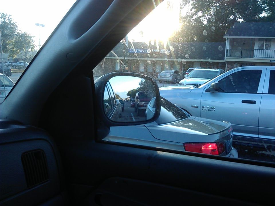 Silver pickup truck in traffic, seen from inside another vehicle, with side mirror reflection.
