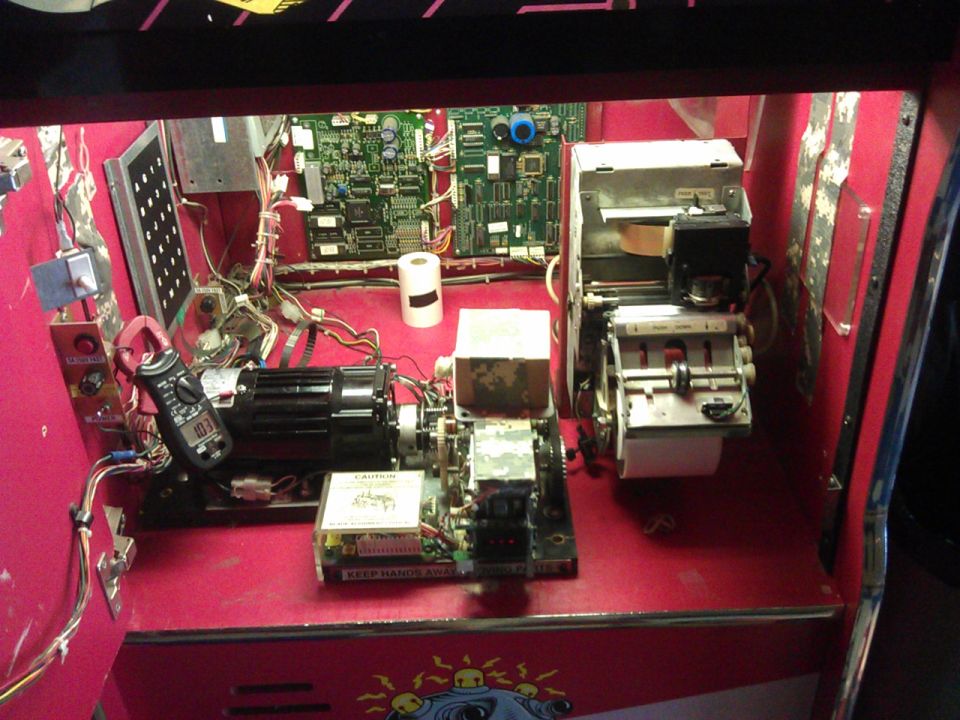 Internal components of a machine with circuit boards, wiring, motor, and paper dispenser.