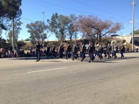 1979 Ford Bronco - A marching band in uniform plays instruments as they parade down a street lined with spectators. The band members are dressed in dark unifo…