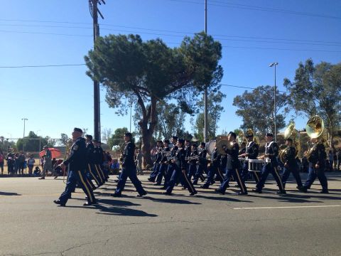 1979 Ford Bronco - A marching band in uniform plays instruments while parading down a street lined with spectators. The band members are dressed in dark unifo…