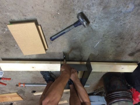 1979 Ford Bronco - A person is cutting a piece of wood with a hand saw. There are pieces of wood and tools on the concrete floor.