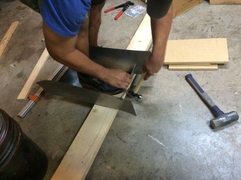 1979 Ford Bronco - A person is cutting a piece of sheet metal with a utility knife, using a wooden jig for guidance. Tools such as hammers and clamps are visi…