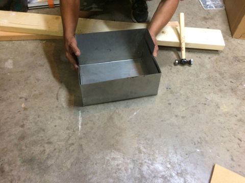 1979 Ford Bronco - A person's hands are holding a metal box on a concrete floor. Two pieces of wood and a hammer are visible in the background.