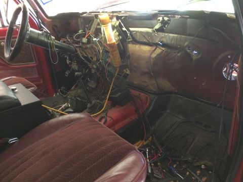 1979 Ford Bronco - The interior of a vintage Ford Bronco shows a disassembled dashboard with extensive wiring exposed. A work light illuminates the complex el…