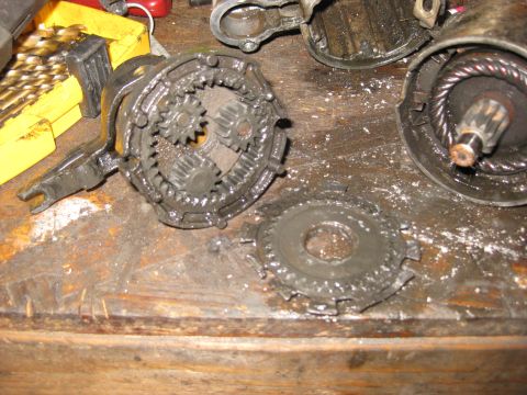 1994 Ford Bronco - A close-up view of a disassembled starter motor assembly, showing gears and wiring, resting on a wooden workbench.