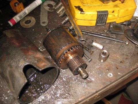 1994 Ford Bronco - A disassembled starter motor armature and housing sit on a workbench next to various tools and hardware. The armature is made of copper win…
