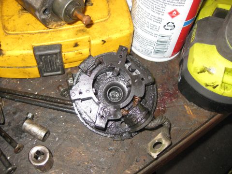 1994 Ford Bronco - A close-up view of a disassembled starter motor component, likely from a 1994 Ford Bronco, resting on a workbench next to a yellow tool cas…