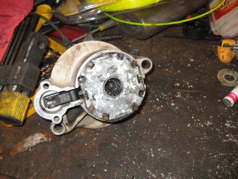 1994 Ford Bronco - A close-up, overhead view shows a disassembled starter motor with a metal housing and a black lever mechanism. The starter is resting on a…