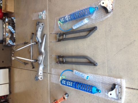 1996 Ford Bronco - A collection of aftermarket suspension parts, including two blue coilover shocks with reservoirs and two fabricated steel control arms, are…