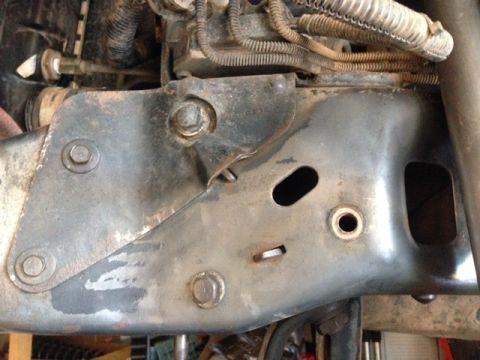 1996 Ford Bronco - A close-up view of the driver's side frame rail of a 1996 Ford Bronco, showing a heavily rusted and modified bracket with multiple bolts an…