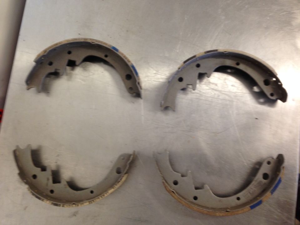 Four curved brake shoes on a metallic surface.