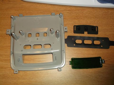 1999 Mercury Grand Marquis - A disassembled gray plastic dashboard trim piece with several mounting screws is shown on a wooden surface. Also visible are two black rubb…