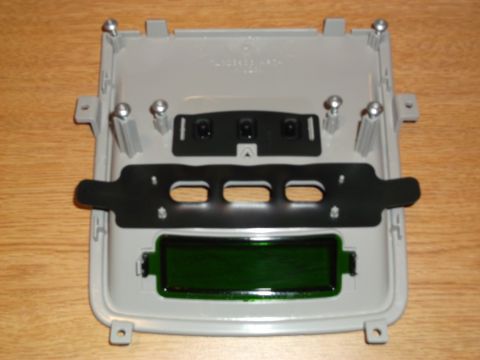 1999 Mercury Grand Marquis - A gray plastic housing with a green digital display and a black metal bracket is shown against a wooden background. Several screws are visi…