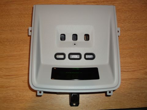 1999 Mercury Grand Marquis - A light gray overhead console part with three buttons labeled LAMP, MODE, and LAMP, and a digital display screen is shown against a wooden…