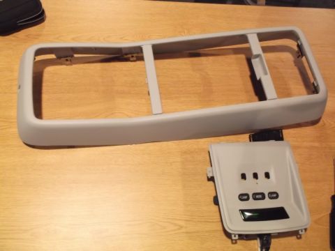 1999 Mercury Grand Marquis - A light gray plastic trim piece and a gray electronic control panel with three buttons and a digital display are laid out on a wooden surfa…