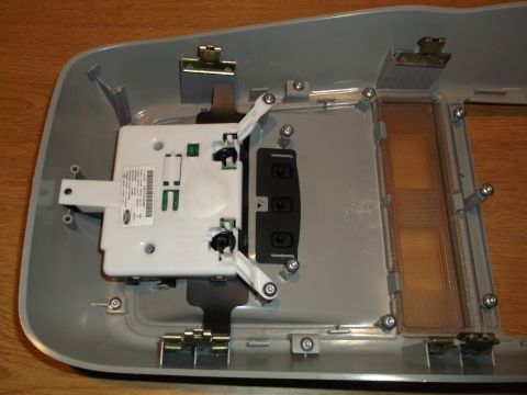 1999 Mercury Grand Marquis - The interior overhead console of a vehicle is shown disassembled. A white electronic module with a Ford logo is visible, along with light l…
