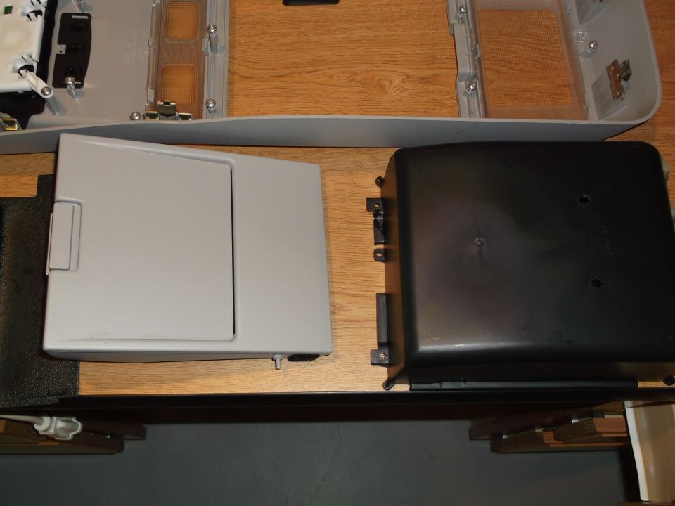Light gray and black automotive interior parts on a wooden table.