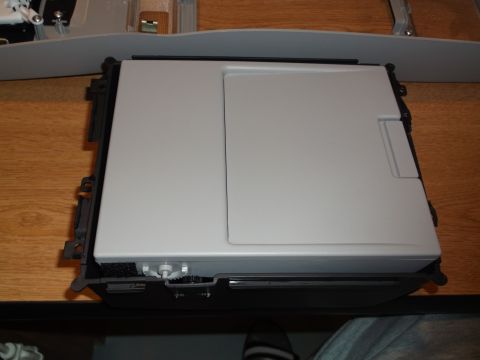 1999 Mercury Grand Marquis - A light gray center console storage compartment with a hinged lid is shown from a top-down angle, resting on a wooden surface.