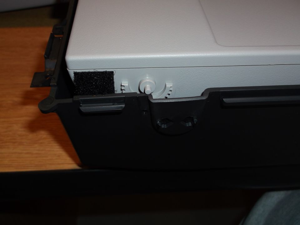 Close-up of a light gray electronic device with velcro and a white dial, inside a black casing.