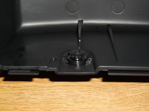 1999 Mercury Grand Marquis - A close-up, overhead view of the interior of a black plastic component, possibly a car part, resting on a wooden surface. A small, black, g…