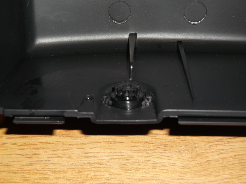 Black plastic car part interior with gear mechanism on wooden surface