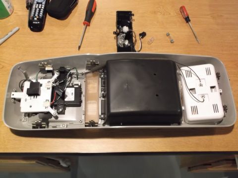 1999 Mercury Grand Marquis - This is a disassembled overhead console assembly, likely from a 1999 Mercury Grand Marquis, laid out on a wooden surface. Various electroni…