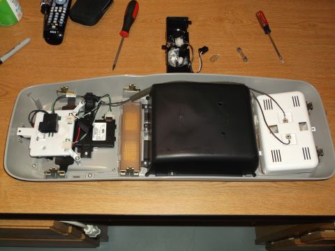 1999 Mercury Grand Marquis - A disassembled overhead console with various electronic components, wiring, and light bulbs laid out on a wooden surface. Tools including s…