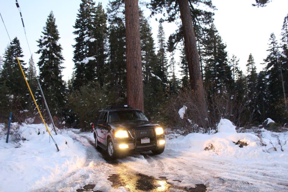 Dark Ford Expedition driving on a snowy road in a forest.