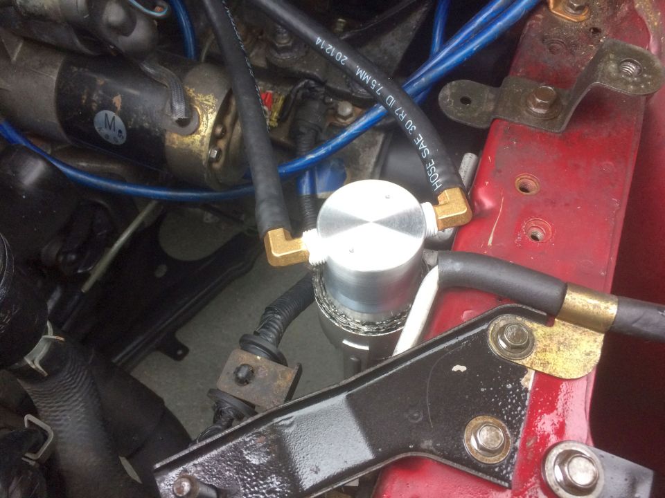 Engine bay with blue and yellow wires, white circular component, and red metal