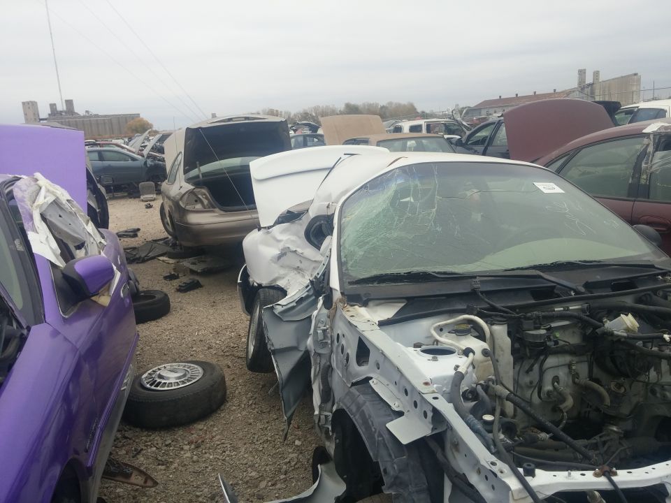 Wrecked white car in a salvage yard